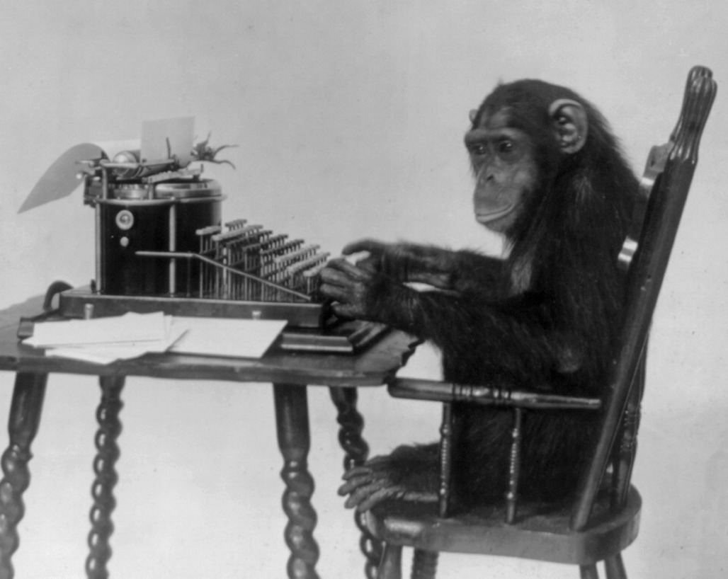 Chimp sitting at a typewriter.